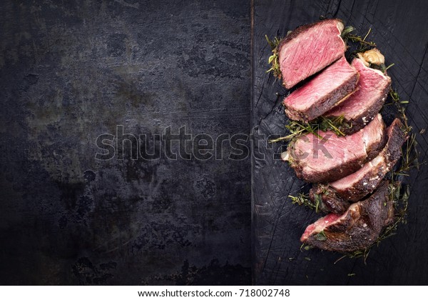 Barbecue dry aged Kobe rib eye steak as\
close-up on a burnt board with copy space left\
