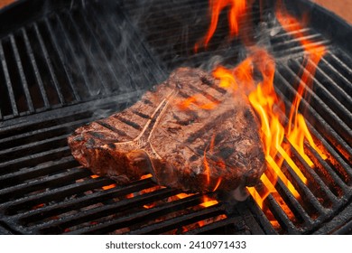 Barbecue dry aged wagyu porterhouse beef steak grilled as close-up on a charcoal grill with fire and smoke  - Powered by Shutterstock