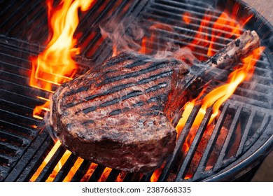 Barbecue dry aged wagyu tomahawk steak offered as close-up on a charcoal grill with fire and smoke  - Powered by Shutterstock