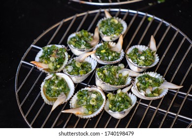 Barbecue grill cooking seafood, grilling seashells with green onion on the island of Phu Quoc, Vietnam, close up