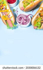 Barbecue grilled fastfood, Various traditional american hot dogs set with sausage, yellow mustard, ketchup and fresh vegetables salad, top view on bright blue background with french fries