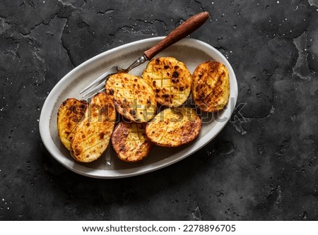 Barbecue grilled potatoes on a dark background top view    