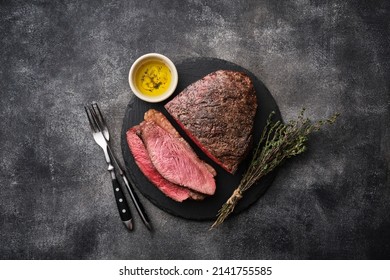 Barbecue Grilled rump cap or brazilian picanha beef meat steak in a wooden tray. Grey background.  Top view, flat lay.