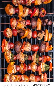 Barbecue Kabobs Smoking On The Grill. Smoked Meat And Vegetables. Grilling Kebabs On The Barbeque. Top View Close Up Selective Focus With Copy Space.