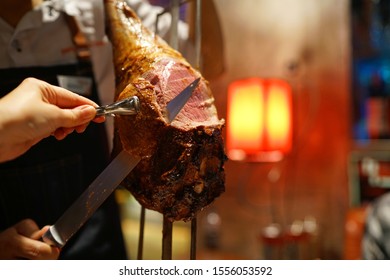 Barbecue Leg Of Lamb On Skewer - Churrasco Brazilian BBQ Cooked On The Rotisserie Served By Cutting Meat Directly Off Skewers Table Side, Dinner Buffet Seafood Night.