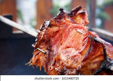Barbecue leg of pig on skewer, closeup. Old spit