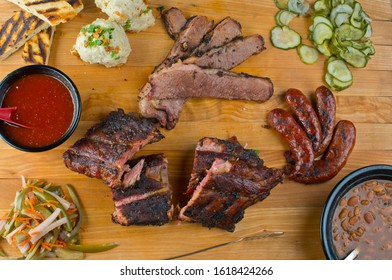 Barbecue Platter. Texas BBQ Platter: Pork Ribs, Brisket, Pork Sausage, Pickles, Bbq Sauce, Potato Salad, Baked Beans.