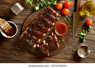 Barbecue pork ribs on cutting board over wooden background. Top view, flat lay