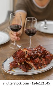 Barbecue Pork Ribs On A Plate, Man Is Holding A Glass Of Wine. Festive 4th Of July Dinner