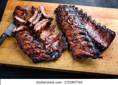 Barbecue pork spare loin ribs St Louis cut with hot honey chili marinade sliced and burnt as closeup on a wooden cutting board 