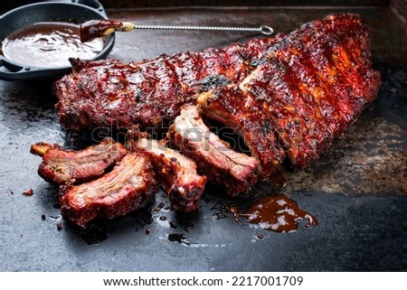 Barbecue pork spare loin ribs St Louis cut with hot honey chili marinade burnt as closeup on an old rustic board 