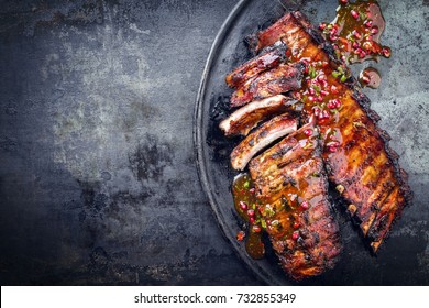 Barbecue pork spare ribs with fruit relish as top view on an old rustic board with copy space 