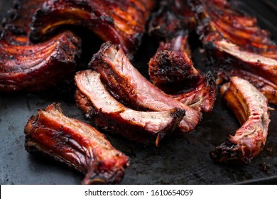 Barbecue Schweinekoteletterrippen St Louis geschnitten mit scharfer Chilimarinade aus Honig, Nahaufnahme auf alten rustikalen Metallplatten 