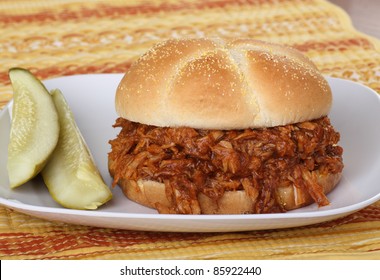 Barbecue pulled pork sandwich on a bun with two pickles