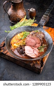 Barbecue roast boar joint with roesti and game red wine sauce as top view in a wrought-iron pan