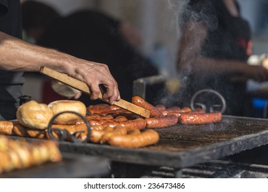 barbecue roasted sausages on a gridiron managed by the hand of a cook with tongs