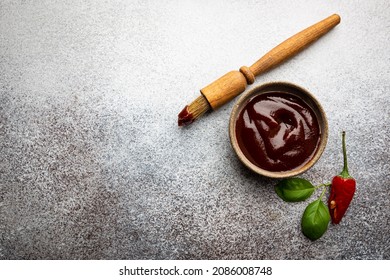 Barbecue Sauce In A Saucer With Basting Brush Over Gray Stone Table, Top View With Copy Space.