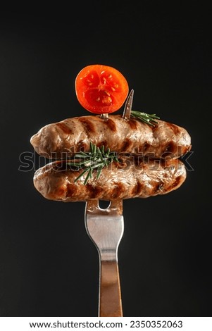 Barbecue sausages with rosemary on a fork. meat sausages in skins with spices, vertical image. place for text.