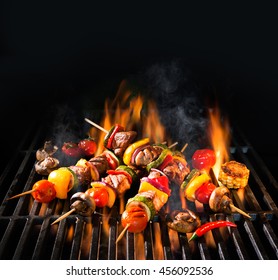 Barbecue skewers meat kebabs with vegetables on flaming grill