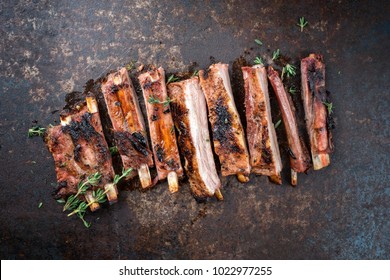 Barbecue spare ribs St Louis cut with hot honey chili marinade sliced as top view on an old rustic board 