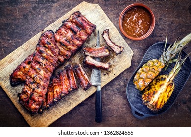 Barbecue spare ribs St Louis cut with hot honey chili marinade and pineapple as top view on a rustic cutting board with copy space 