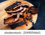 Barbecue spareribs St Louis cut with hot rub and BBQ sauce served as close-up on a wooden design board