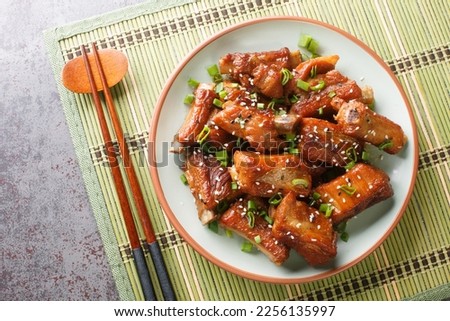 Barbecue sweet and sour spire ribs with green onion and sesame close-up in a plate on the table. Horizontal top view from above
