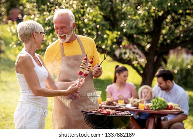 Barbecue time.Senior couple is standing by the grill and having fun while baking meat. - Powered by Shutterstock