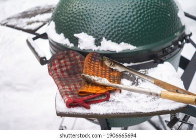 Barbecue tongs and protective gloves on a portable cooker, winter scene