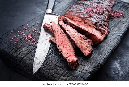 Barbecue wagyu bavette beef steak with red wine salt offered as close-up on charred wooden black board