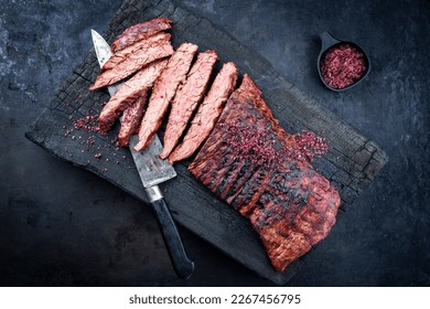 Barbecue wagyu bavette beef steak with red wine salt offered as top view on charred wooden black board 