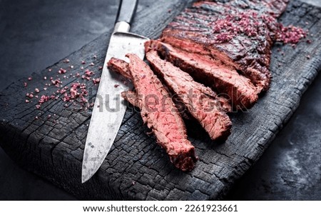 Barbecue wagyu bavette beef steak with red wine salt offered as close-up on charred wooden black board