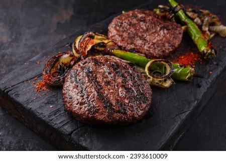 Barbecue wagyu beef Hamburger with grilled chili and onion rings served as close-up on a charred wooden board 