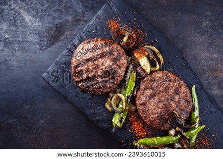 Barbecue wagyu beef Hamburger with grilled chili and onion rings served as top view on a charred wooden board with copy space left