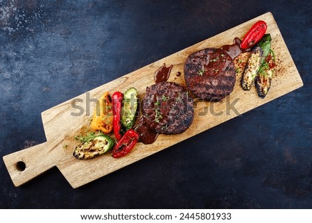 Barbecue wagyu beef Hamburger with grilled vegetable and spicy sauce served as top view on a design wooden cutting board with copy space 