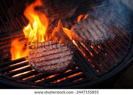 Barbecue wagyu beef Hamburger grilled as close-up on a charcoal grill with fire and smoke 