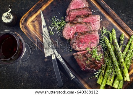 Barbecue Wagyu Point Steak with green Asparagus as close-up on burnt cutting board 