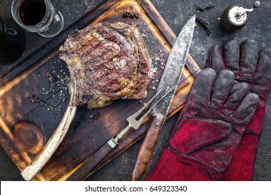 Barbecue Wagyu Tomahawk Steak As Top View On Burnt Cutting Board 