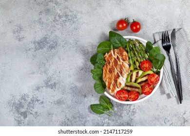 Barbecued chicken breasts and fresh green vegetable and chery tomatoes in a white plate. view from above. ketogenic diet - Shutterstock ID 2147117259