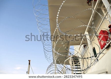Barbed or razor wire attached to the ship hull, superstructure and railings to protect the crew against piracy attack passing Gulf of Guinea in West Africa.