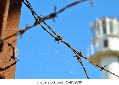 Barbed Wire Against The Backdrop Of The Prison Watchtower.