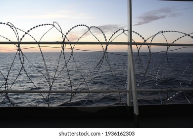 Barbed Wire Attached To The Ship Hull, Superstructure And Railings To Protect The Crew Against Piracy Attack In The Gulf Of Guinea In West Africa Sailing During Sunset.