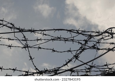 barbed wire attached to the wall of the house with a cloudy sky as a background
