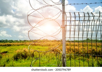 Barbed wire barrier in restricted area, barbed bottom view and morning sun, Barbed wire fence and wire mesh with sky, Fence with barbed wire against the blue sky.