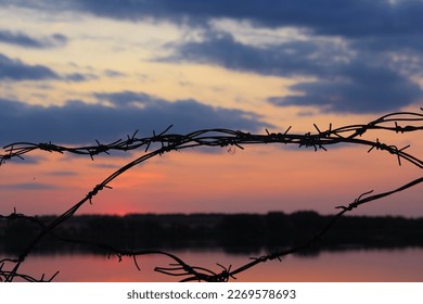 Barbed wire by the river at sunset