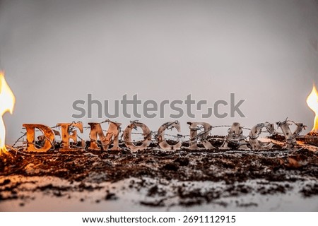 Barbed wire envelops charred and battered wooden letters spelling out the word 