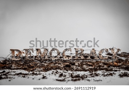 Barbed wire envelops charred and battered wooden letters spelling out the word 