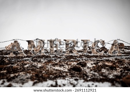 Barbed wire envelops charred and battered wooden letters spelling out the word 