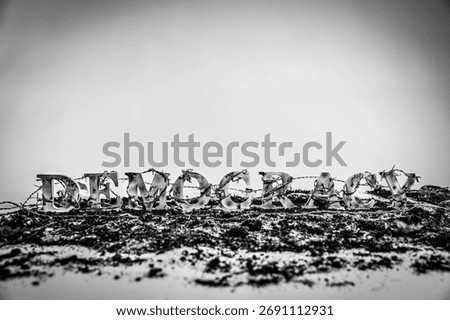 Barbed wire envelops charred and battered wooden letters spelling out the word 