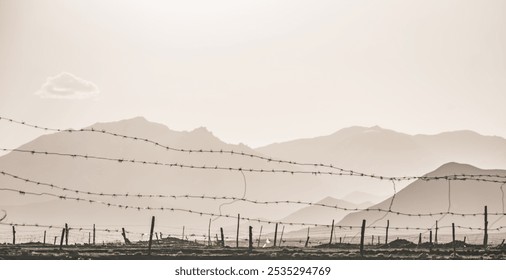 Barbed wire fence against the backdrop of mountain ranges in the Pamir Mountains in Tajikistan - Powered by Shutterstock